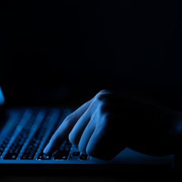 Dark hand pressing a button on laptop